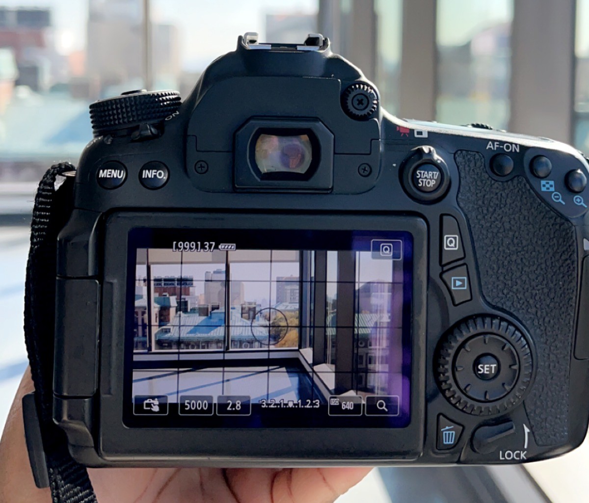 A DSLR camera facing a window looking out at the buildings of Columbia University