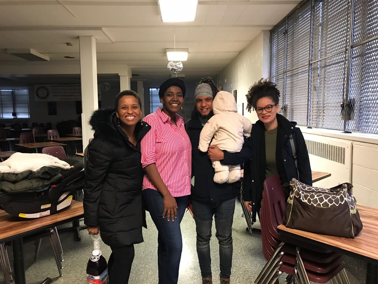 Miriam Neptune, Altagracia Jean Joseph, Alexis Francisco, and another facilitator stand in a row posing for the photo. Miriam is also holding a baby.