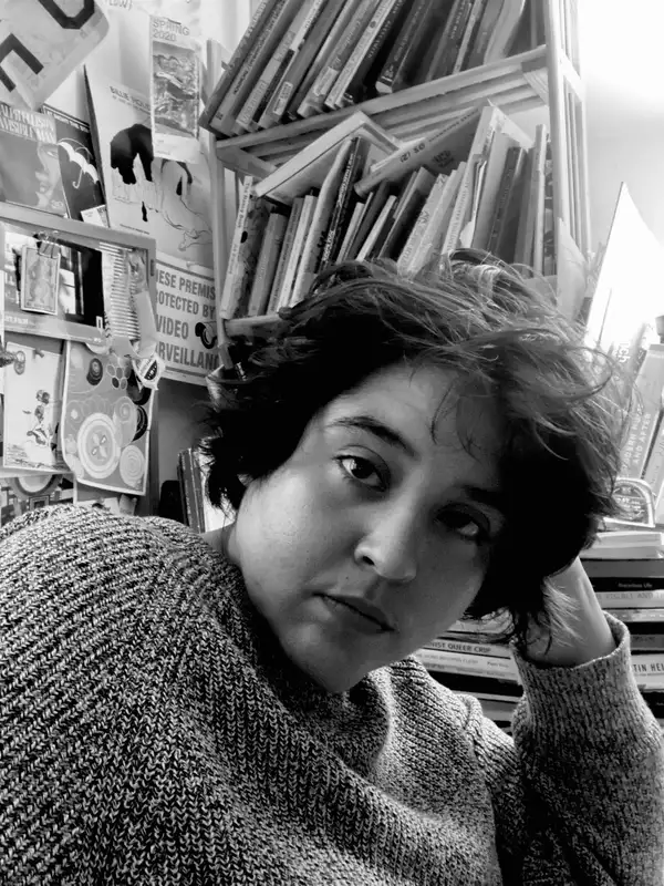 black and white headshot of an individual in front of a bookcase